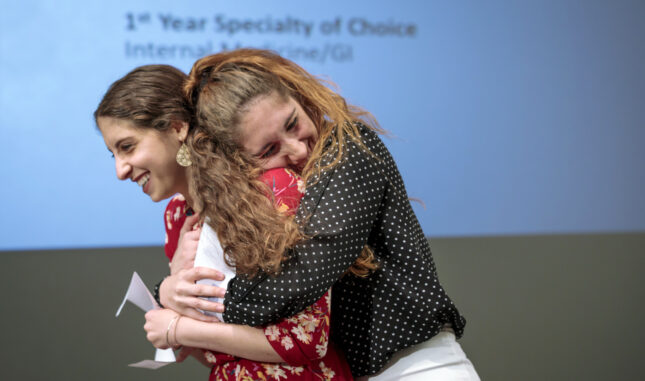 A graduating student and her partner hug after learning where she matched for residency