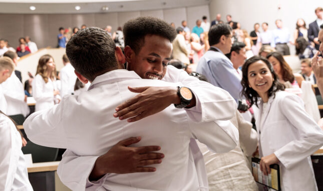 Two incoming students hug after taking oath at White Coat Ceremony